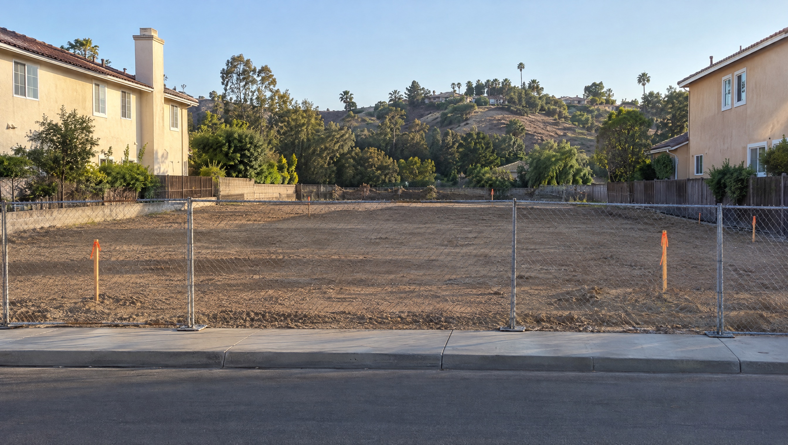 Before: vacant graded lot with construction fence